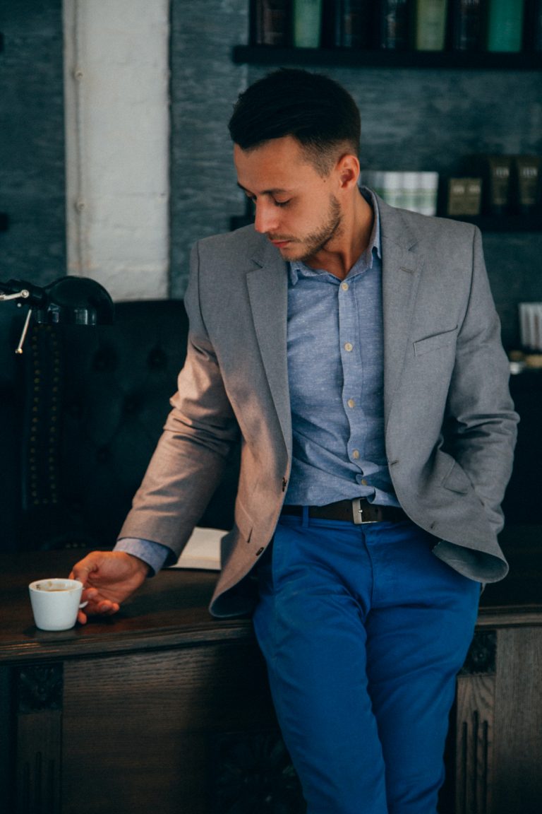 man in suit looks down at coffee cup